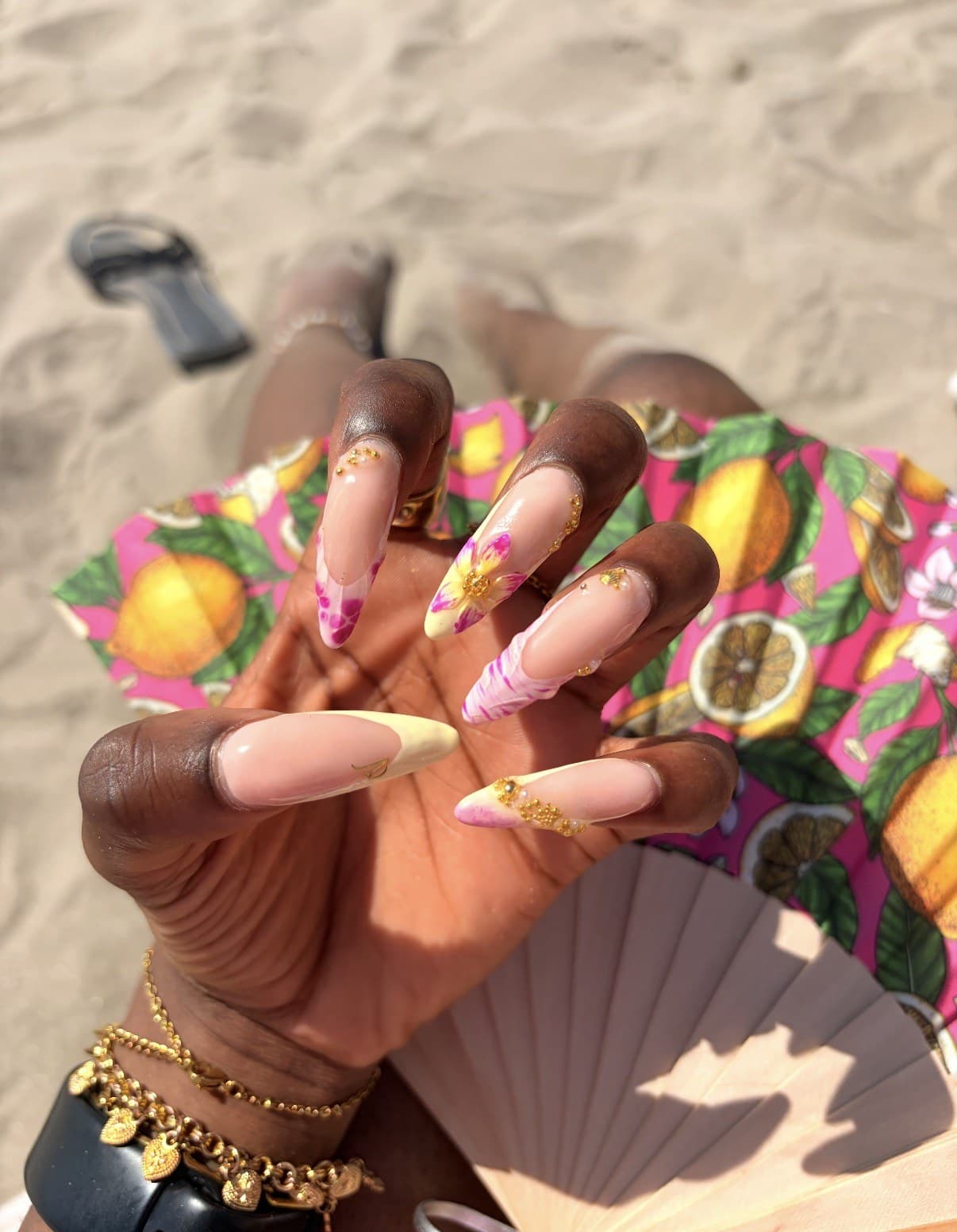 Almond nails with hand-painted pink and yellow florals, gold caviar beads and marble tips