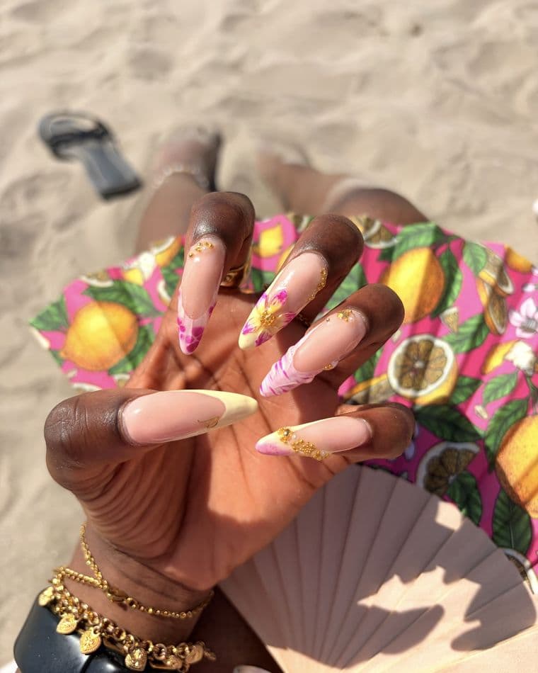 Almond nails with hand-painted pink and yellow florals, gold caviar beads and marble tips