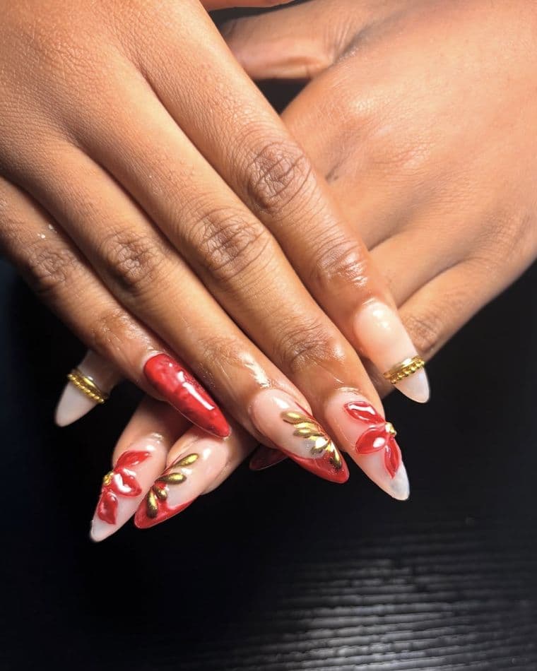 Stiletto nails with 3D red petals and gold foil leaves on a milky base