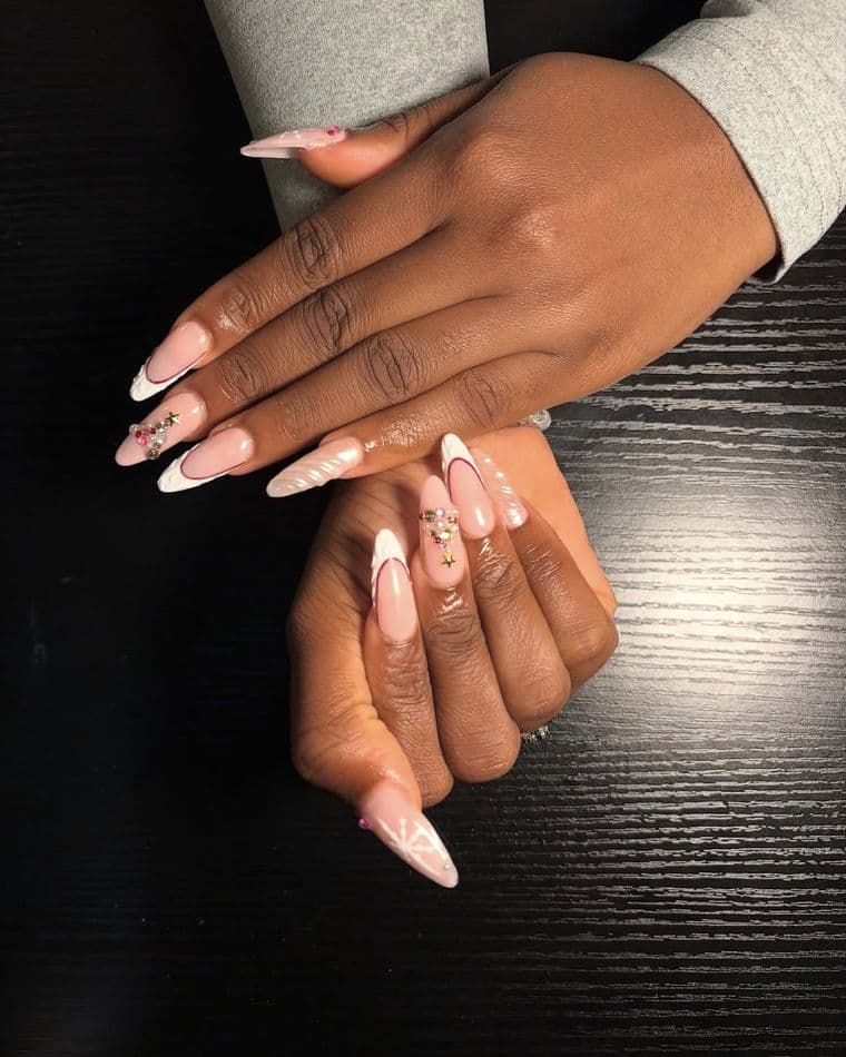 Almond nails in milky pink with white french tips and a gem cluster