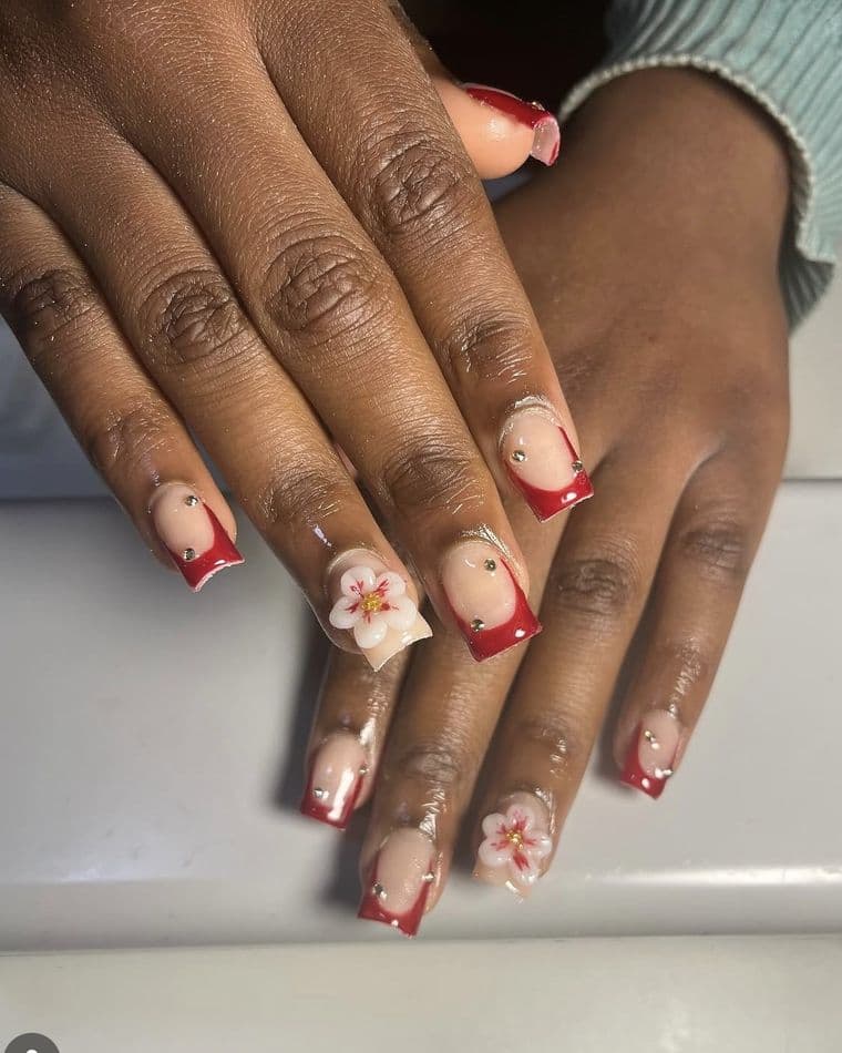 Square nails with red french tips, 3D white blossoms and gold studs